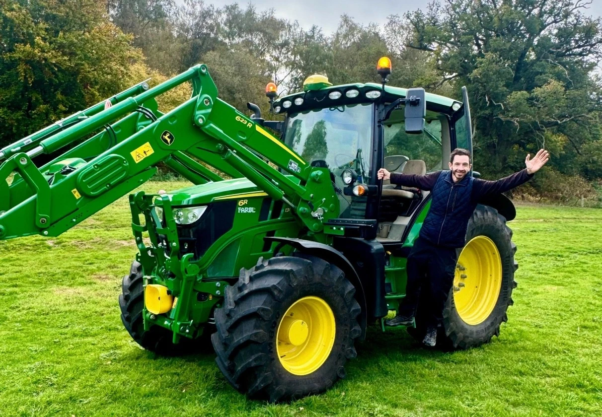 Participant beside a modern agricultural tractor during a tractor driving experience